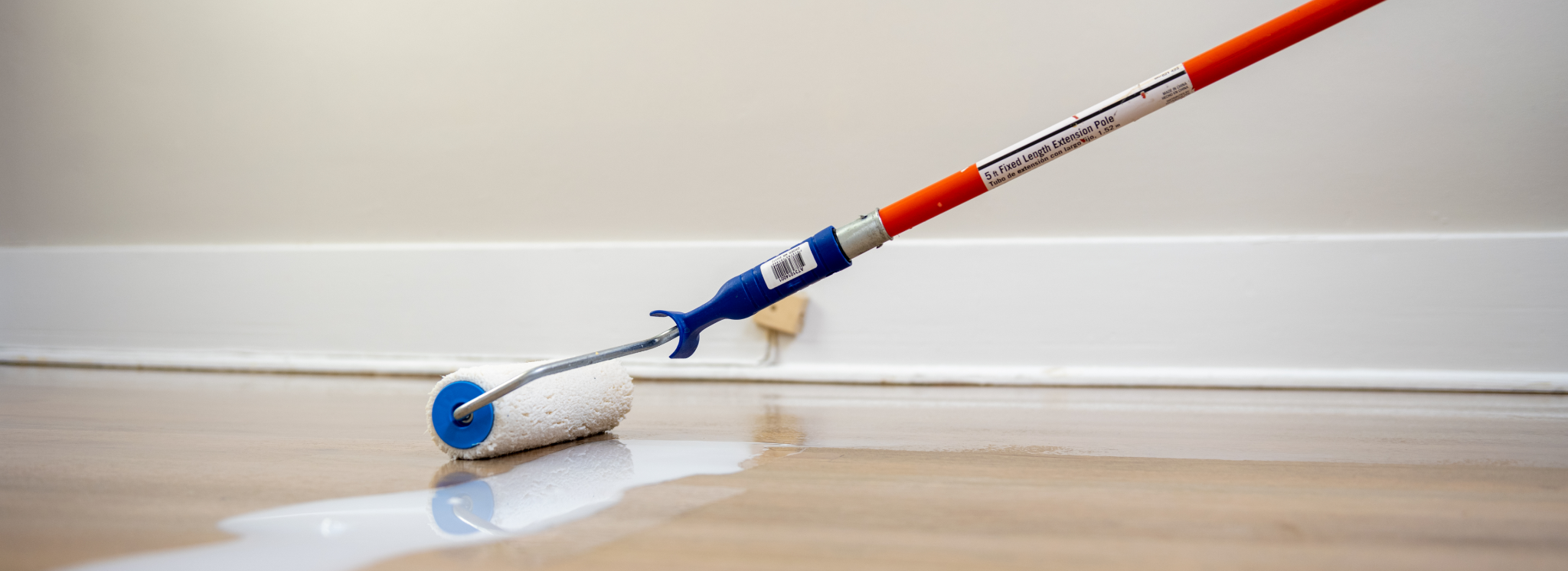 Close-up of a professional applying a whitewash sealant with a roller to freshly sanded oak plank flooring—capturing the finishing stage of Wood Floor Sanding in Woking.