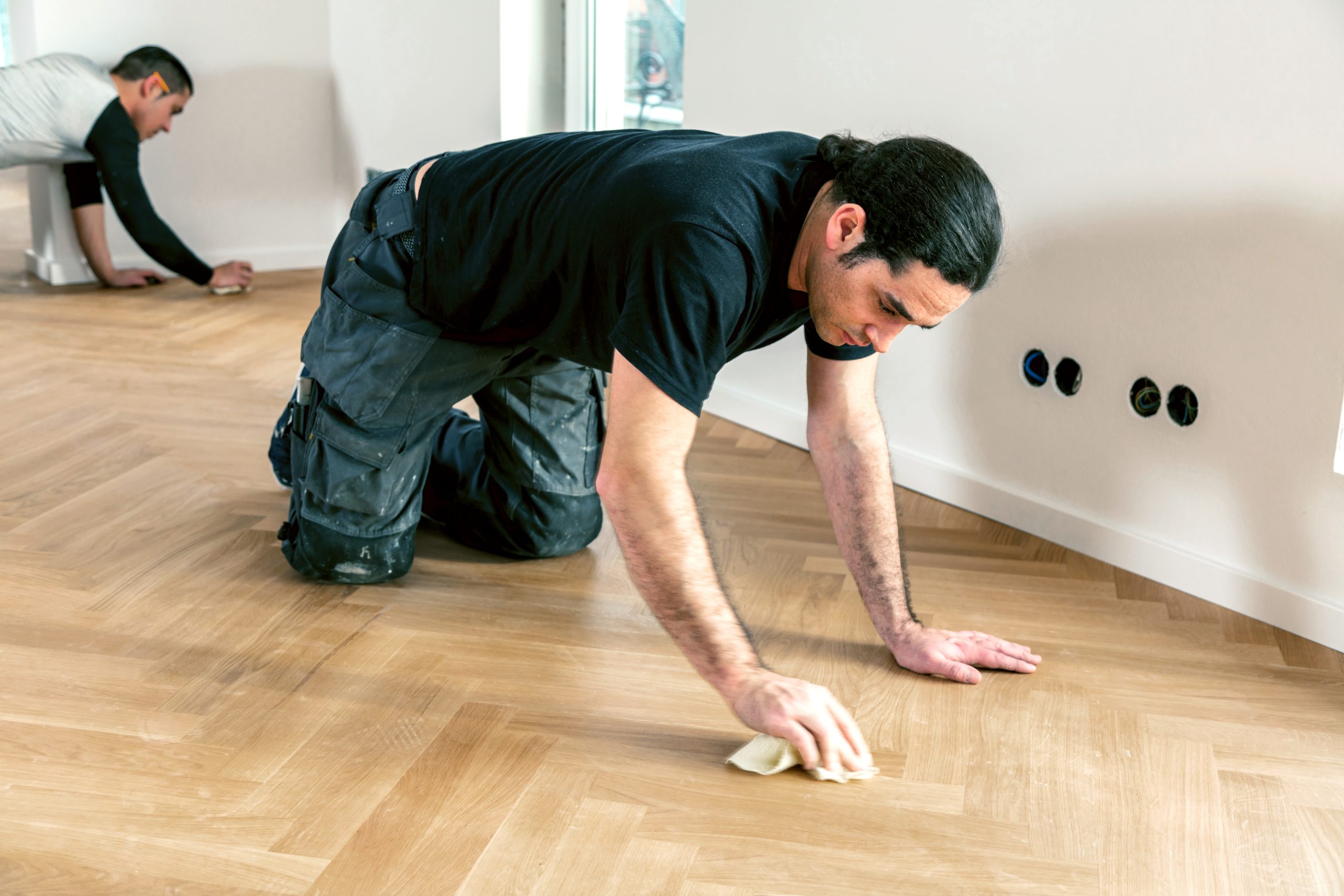Furious Fixes in Woking: technicians hand-buffing a herringbone oak parquet floor to restore a smooth, even satin sheen.