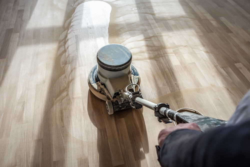 Furious Fixes in Woking: low-speed buffer polishing an oak laminate plank floor to restore an even, satin sheen and blend light traffic marks.