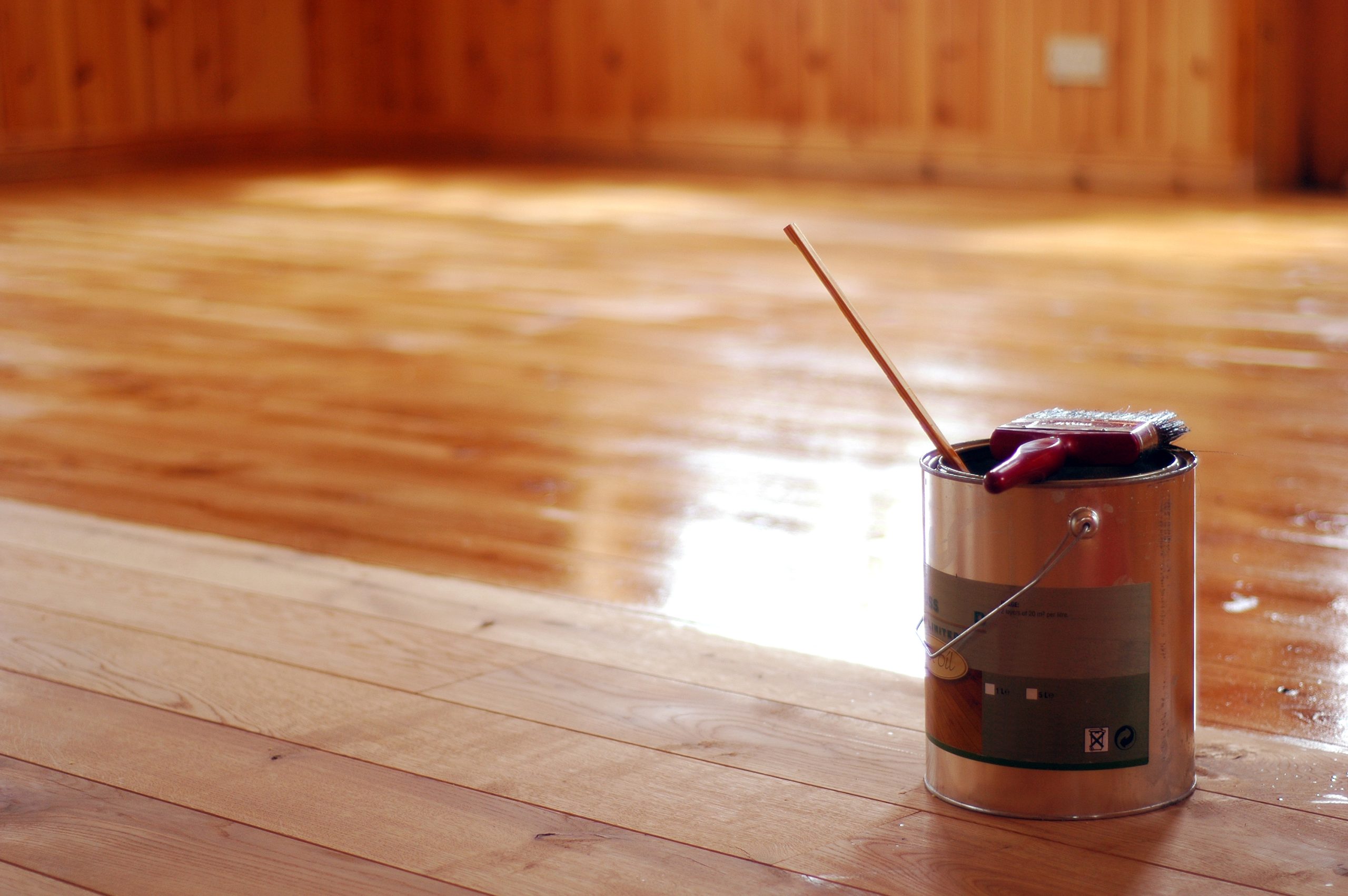 Furious Fixes in Woking: solid softwood pine floorboards mid-treatment, tin and brush on site, showing matte-to-gloss transformation after waxing.