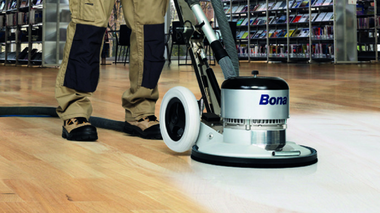 Wood Floor Sanding in Woking on a light hardwood strip floor in a commercial space, using a Bona rotary sanding machine for a smooth, dust-controlled finish.