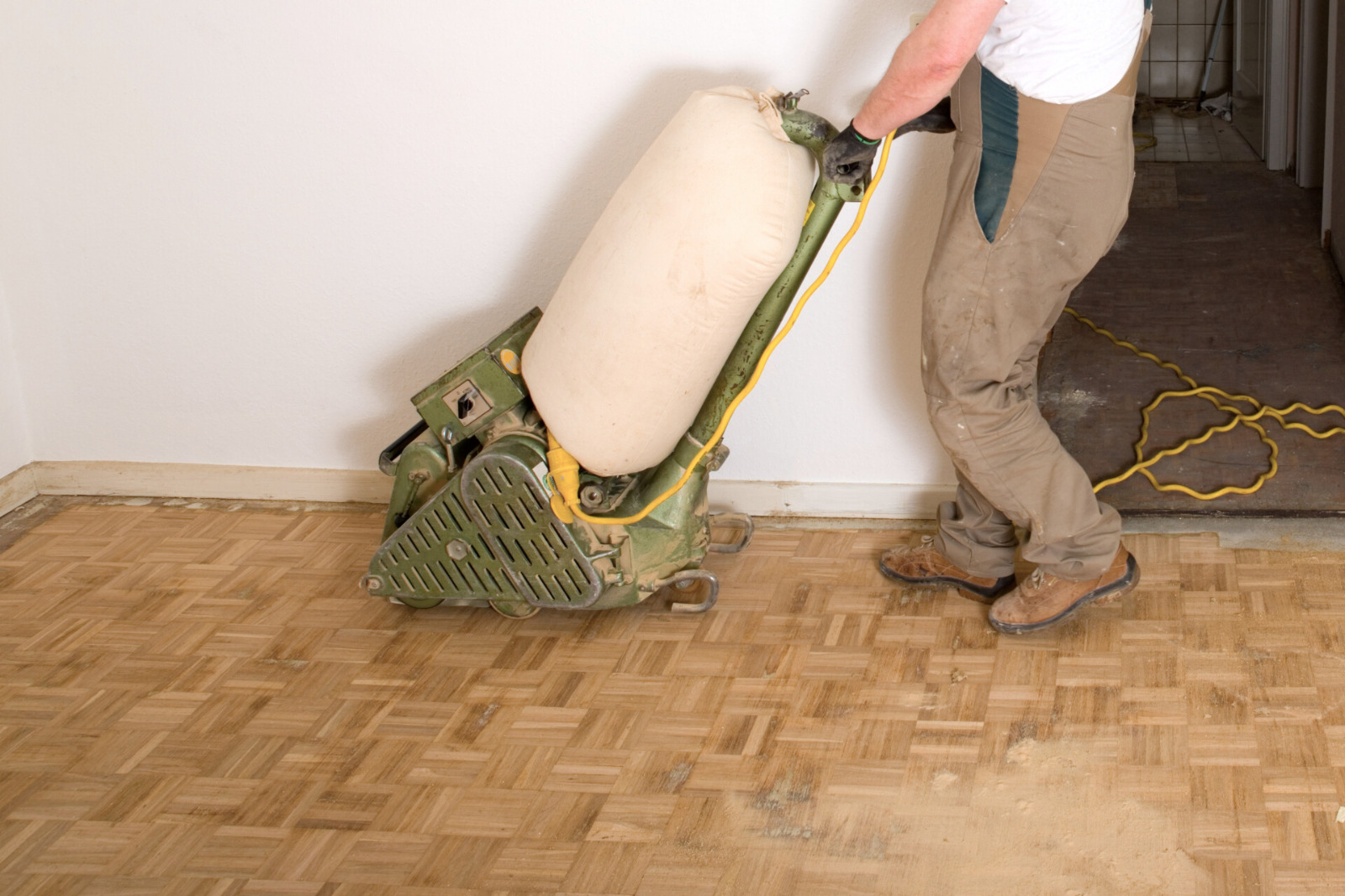 Wood Floor Sanding in Woking – technician using a drum sander on an oak mosaic parquet floor, stripping back the old finish for restoration.