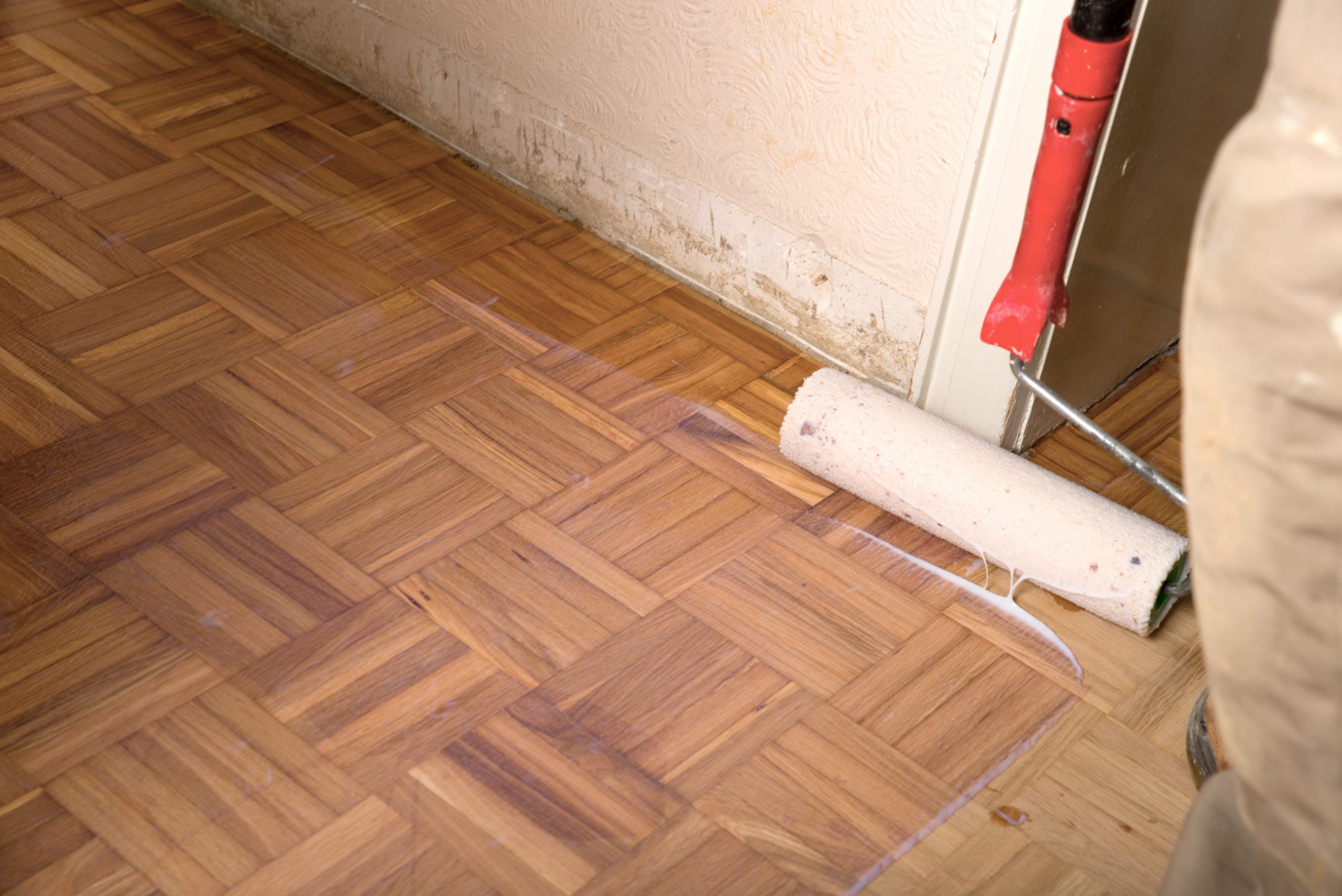 Wood Floor Sanding in Woking on an oak mosaic parquet floor, with a roller applying clear sealant after sanding for a smooth, protected finish.