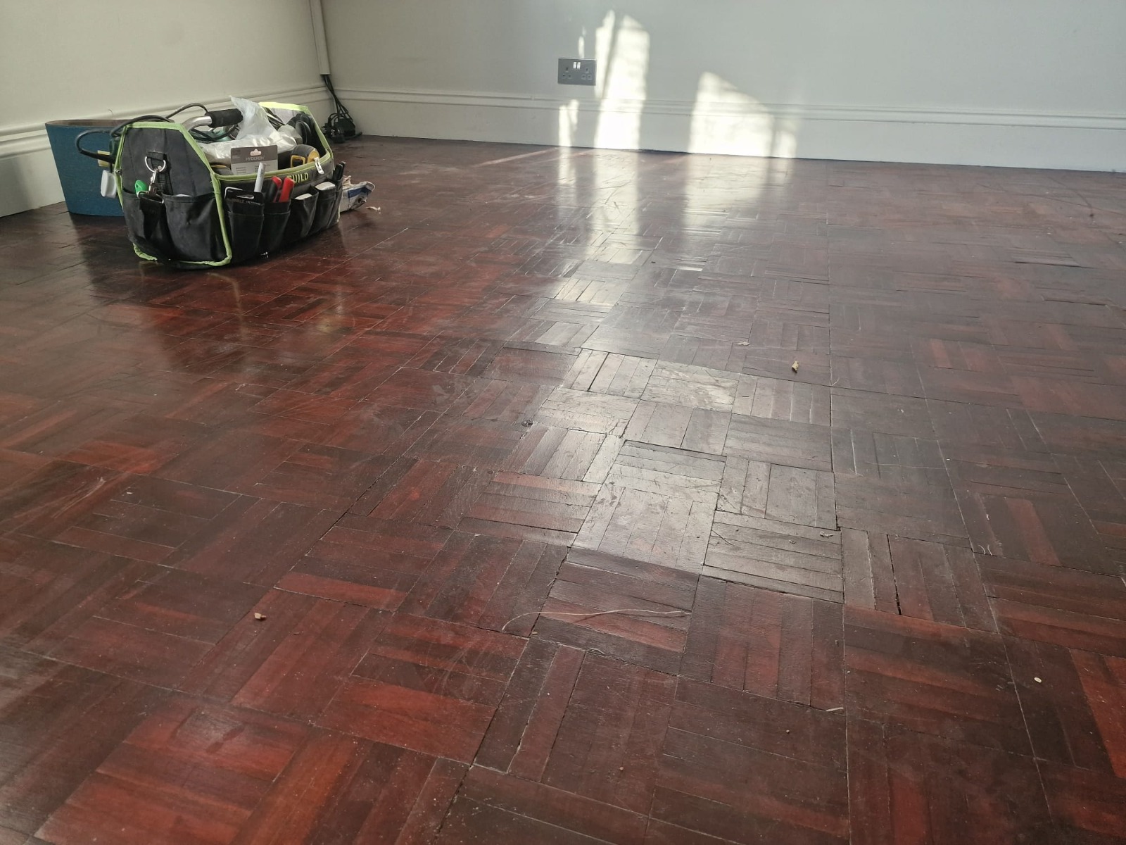 Wood Floor Sanding in Woking on a dark-stained oak mosaic parquet floor, showing worn, scratched blocks ready for restoration.