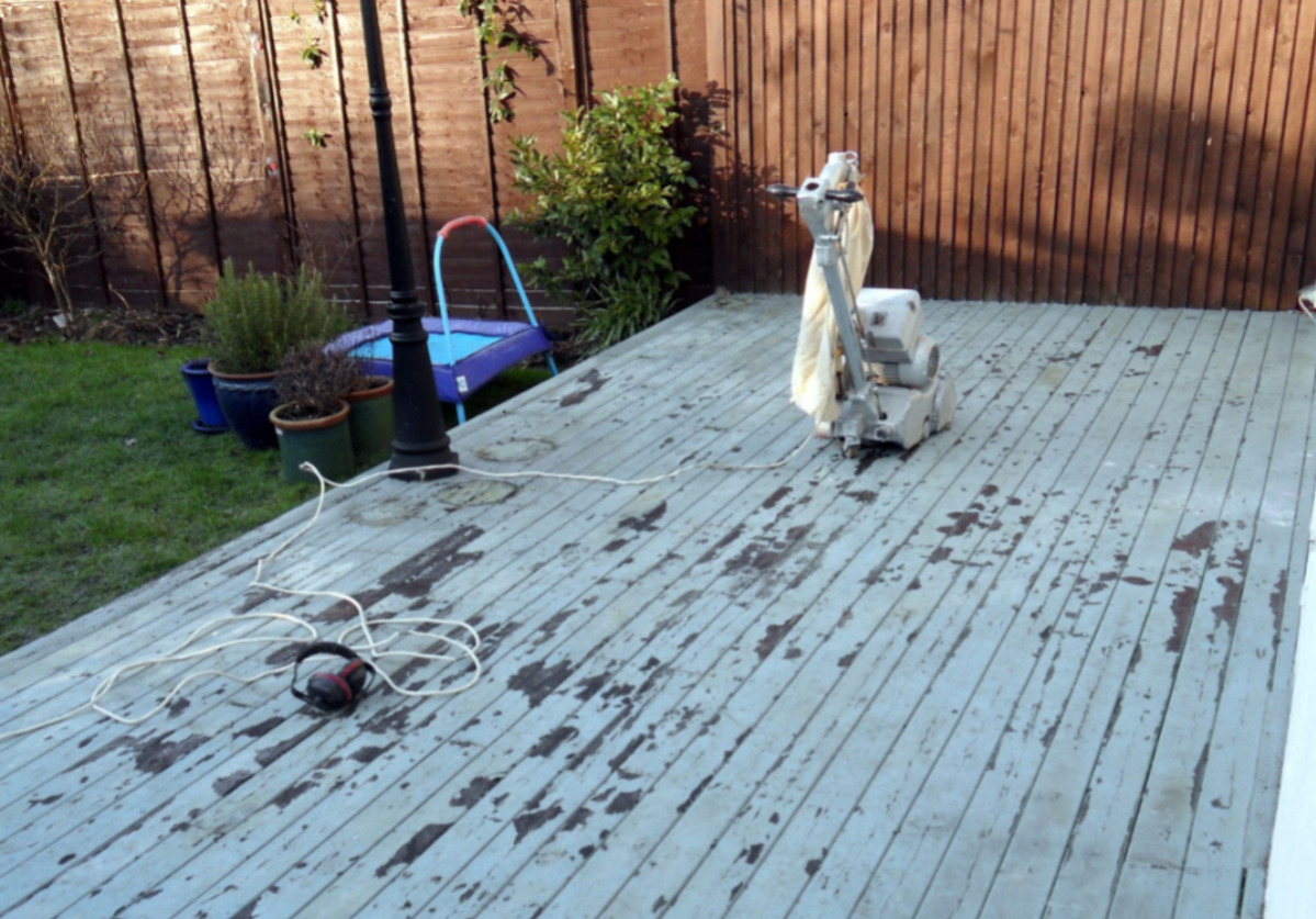 Wood Floor Sanding in Woking on a painted softwood decking floor, showing a garden deck with peeling paint being prepared with a professional sanding machine.